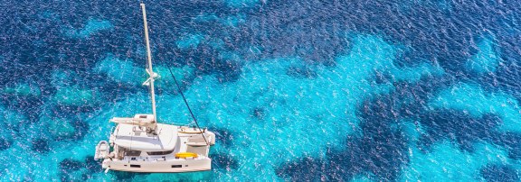 Catamaran on engine in azure Greek water