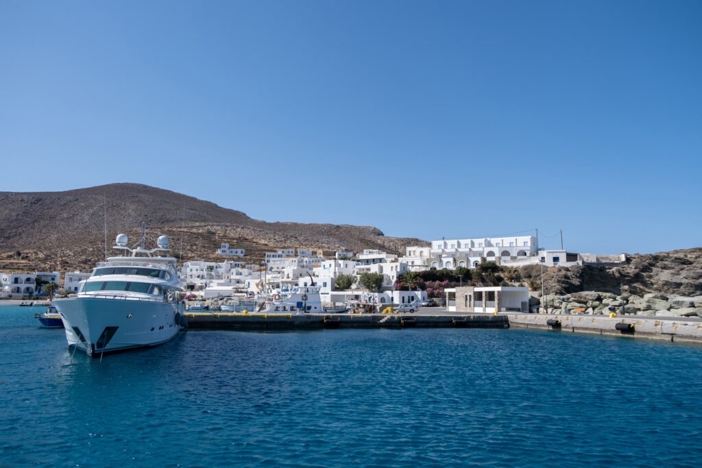 Yacht moored at Folegandros greek island port. Cruise motor boat anchored at Karavostasi dock-min.