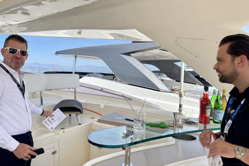 Charter broker John Boullin on the flybridge of a motor yacht at the MEDYS yacht show, brochure in hand