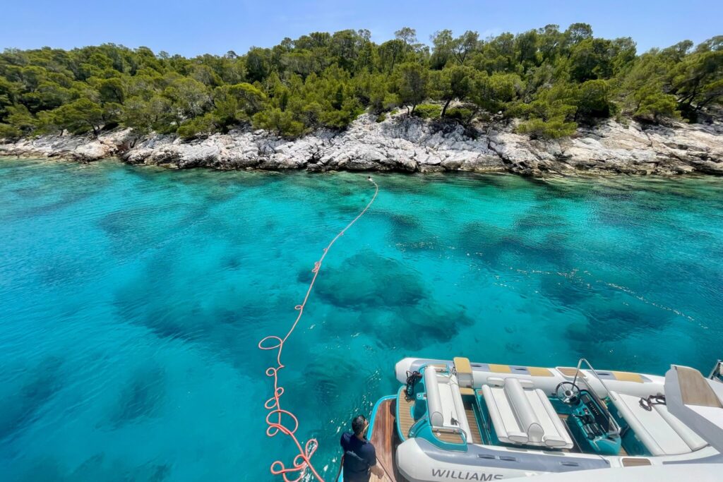 Deckhand swims ashore with the stern line to tie off to the rocks at Agistri Island, motor yacht ANKA