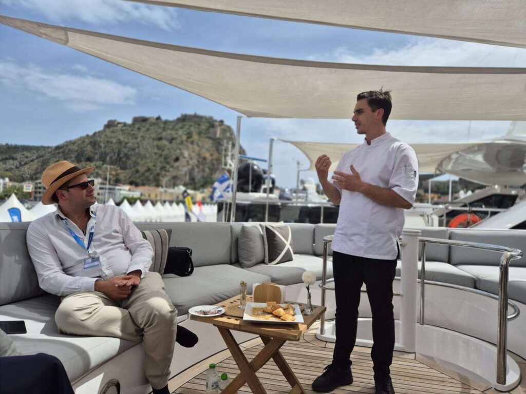 Mo Pristas of DMA Yachting talking with Chef Nikos on the aft deck of motor yacht MILOS at a yacht show