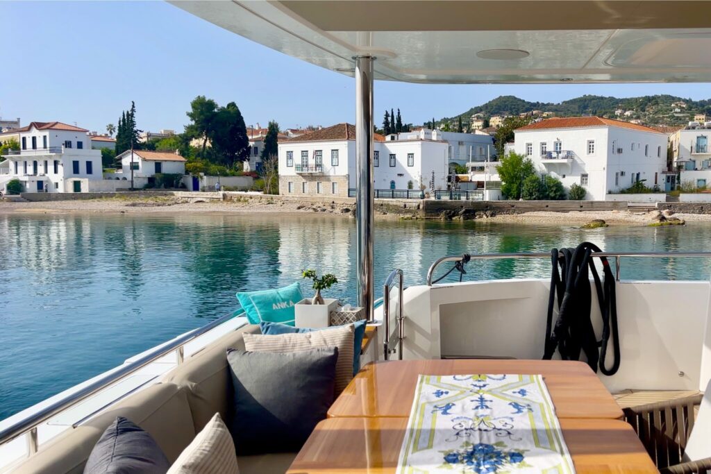 Arriving at Spetses on the aft deck of motor yacht ANKA, white mansions along the waterfront