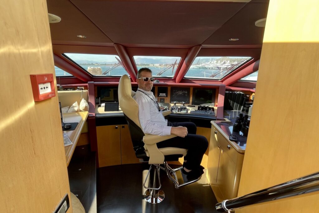 Charter broker John Boullin sitting in the captain's chair on the bridge of a motor yacht
