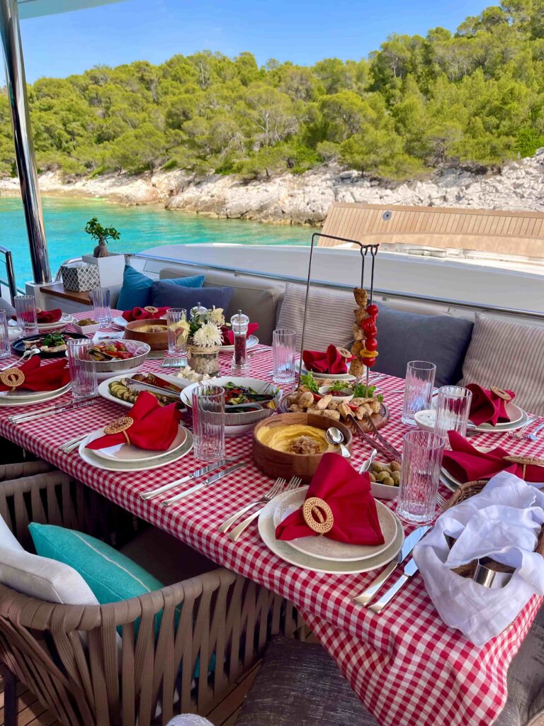 Greek meze lunch laid on the aft deck of motor yacht ANKA in a pine-fringed cove
