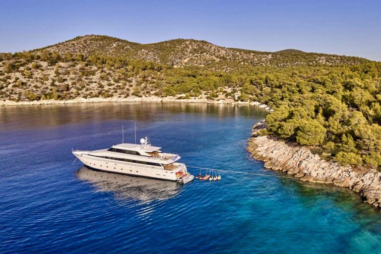 Greek luxury motor yacht LET IT BE with stern tied to the rocks off Greek Island