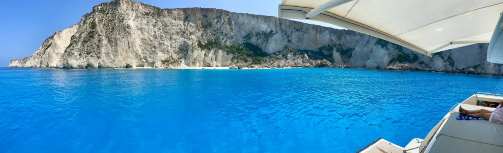 Luxury yacht charter anchored by dramatic white cliffs and turquoise waters in the Ionian Sea, Greece.
