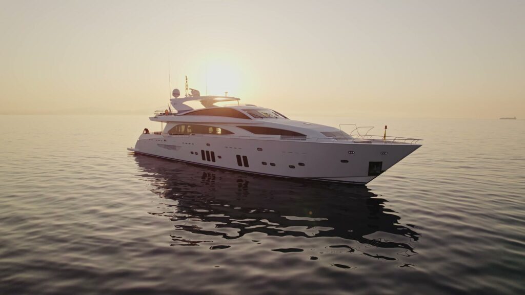 The 121 ft Couach motor yacht HAKUNA MATATA at anchor on a calm sea at sunset in Greece