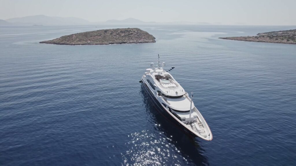 Benetti superyacht SUNDAY at anchor off a small rocky islet, seen from the air