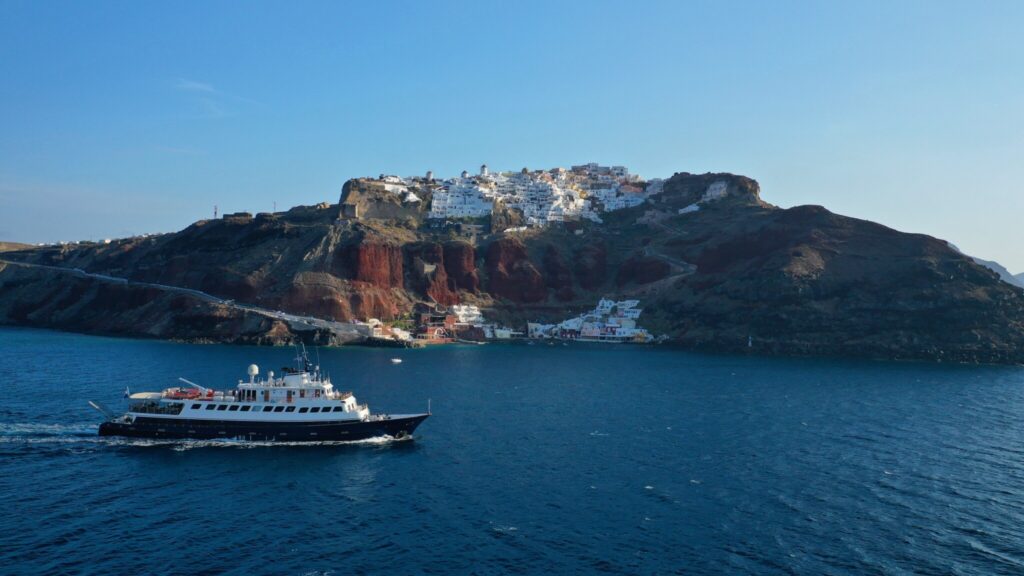 Large motor yacht cruising below the village of Oia on Santorini