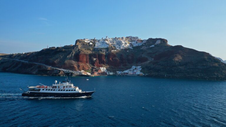 Large motor yacht cruising below the village of Oia on Santorini