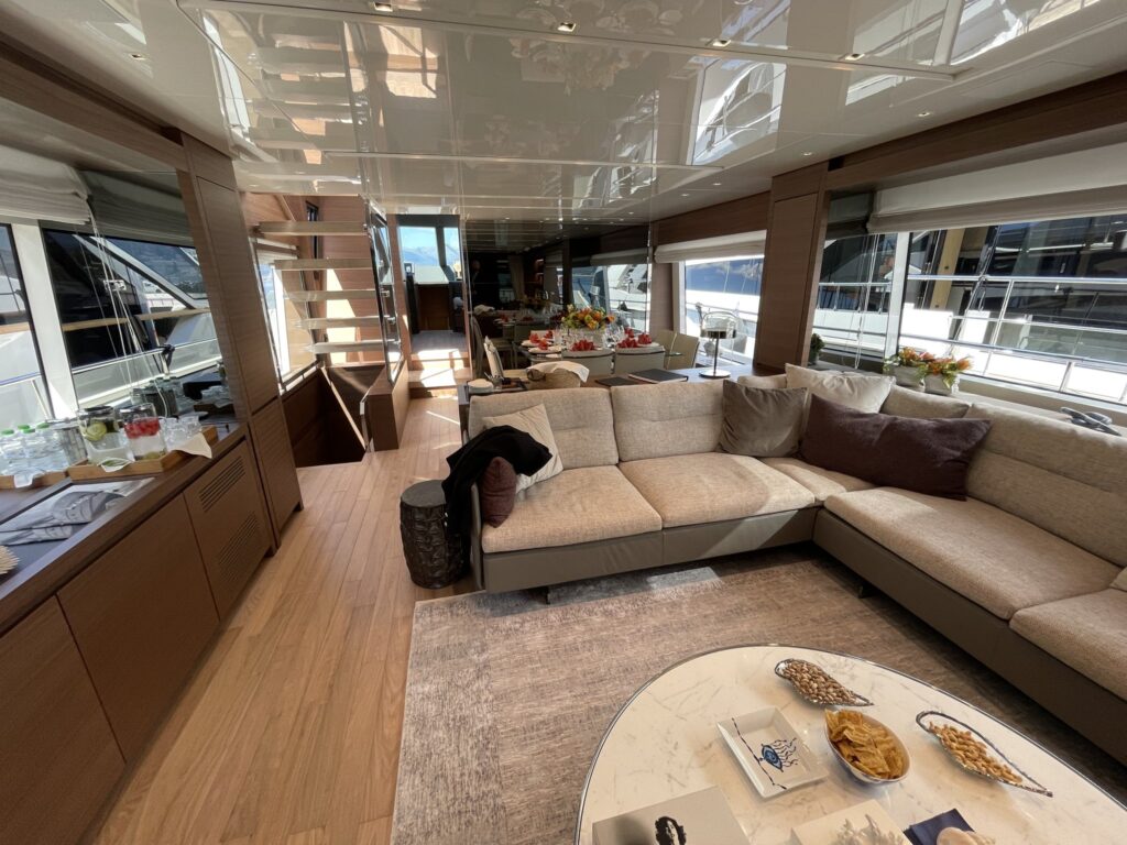The main saloon of motor yacht AKASTI with a large sofa and coffee table, May 2026.