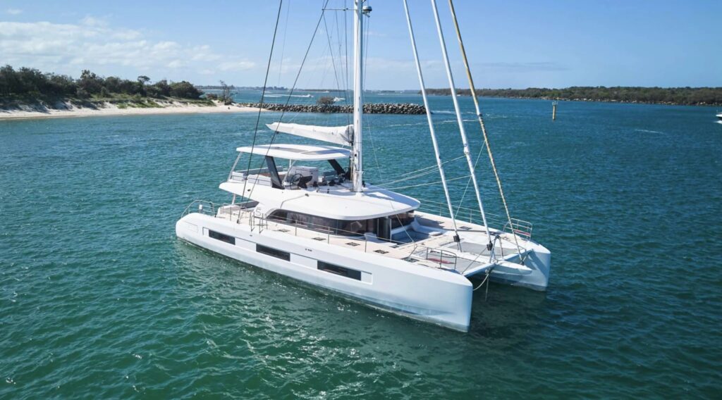 AMAREA, a 2026 67 ft Lagoon sailing catamaran for eight guests, at anchor off a beach in Greece