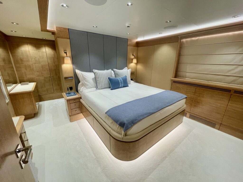 A double guest cabin on ARTEMISEA with a blue throw and oak panelling