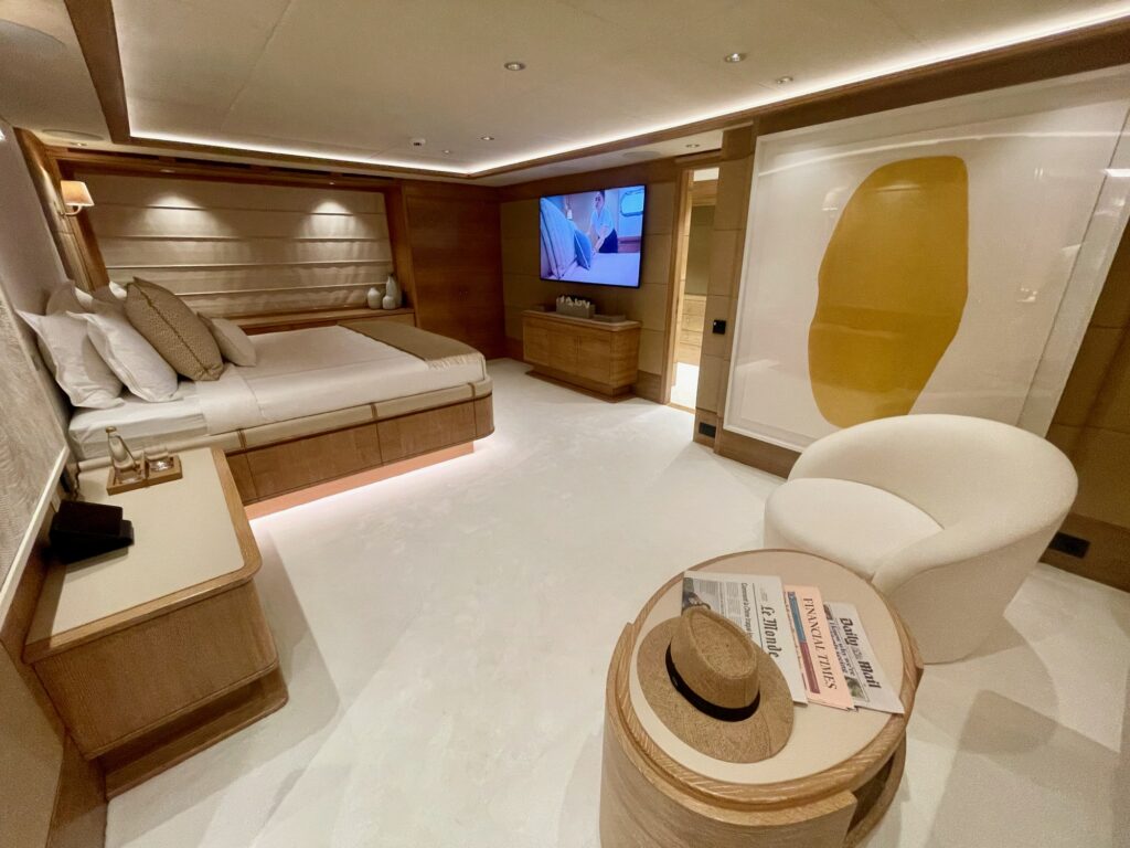 ARTEMISEA's full-beam master cabin with the bed, armchairs and a wall TV
