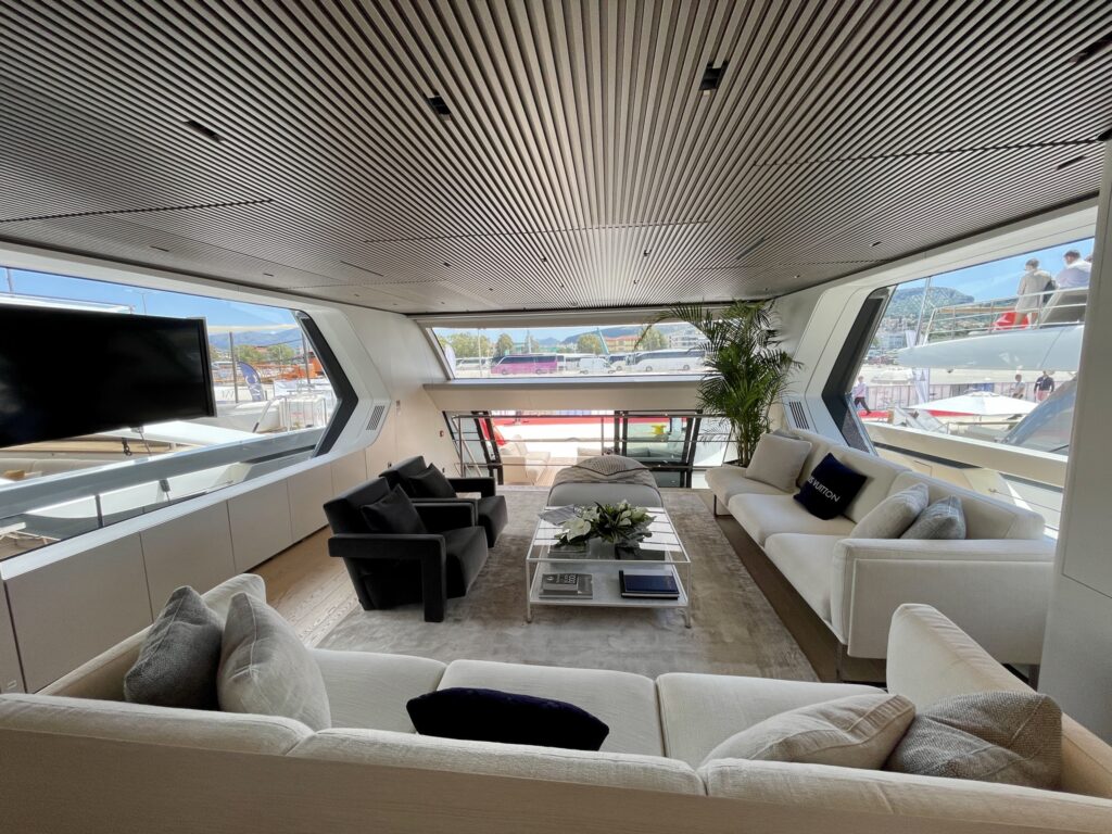 The upper saloon of motor yacht BESTIA, with wraparound windows and a lounge facing aft, May 2026.