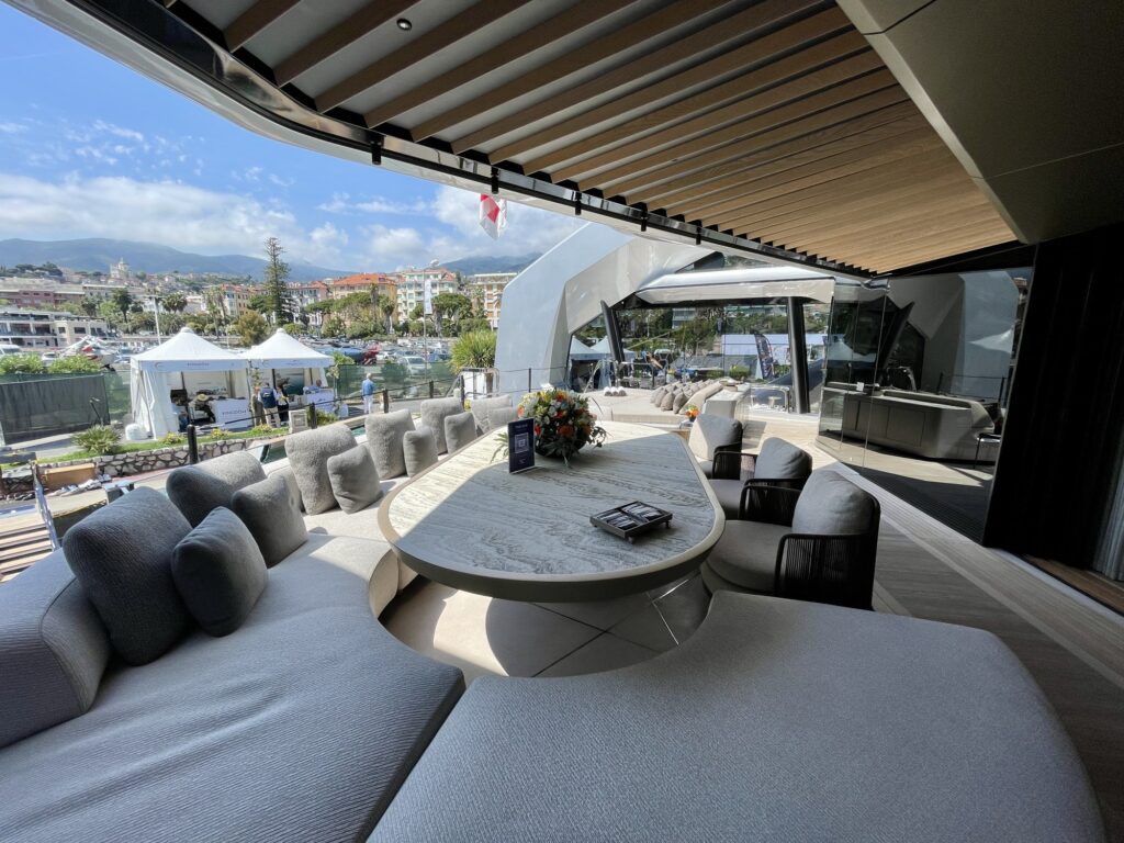 Curved sofas and a round stone table on the aft deck of THIS IS IT, open to the marina