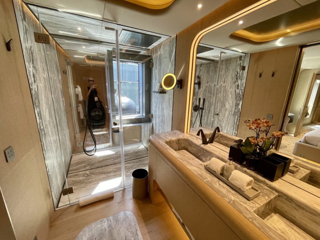 Marble bathroom with a glass shower and curved mirror on THIS IS IT