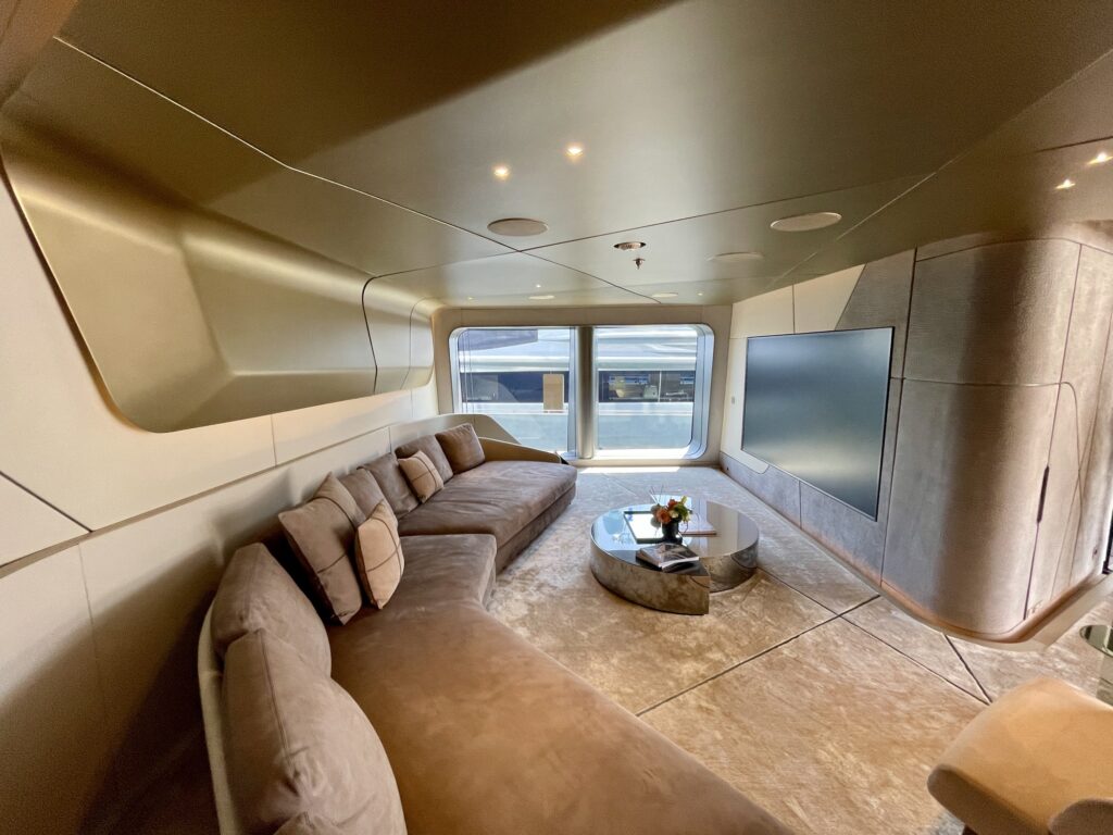Suede corner sofa, mirrored coffee table and a wall-mounted screen in a THIS IS IT lounge