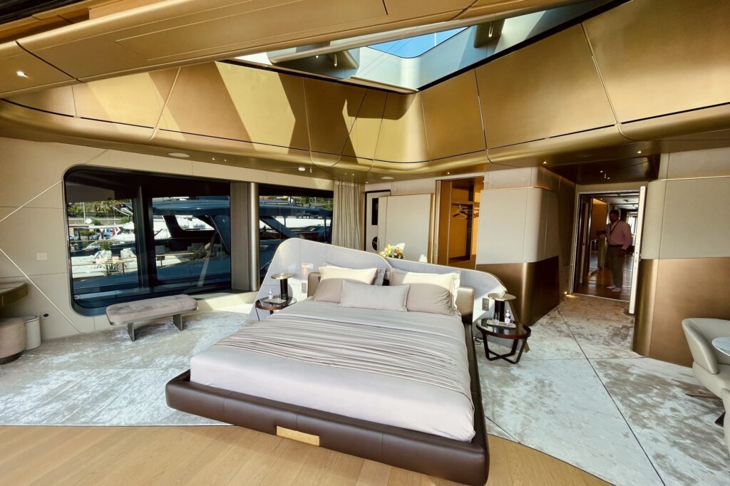 Sculpted white bed on a dark base under the skylight in the master cabin of THIS IS IT