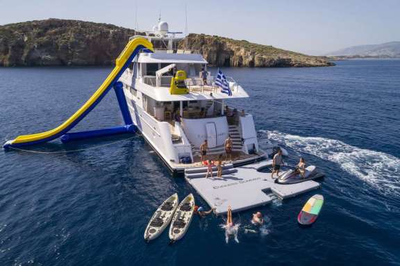 Water slide and floating platform with jet ski docks and other toys on motor yacht endless summer