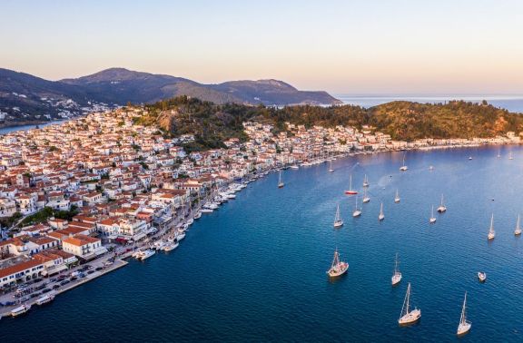 Aerial View of the Promenade at Poros, Greece with many yachts moored along the waterfront and more on anchor in front of the town