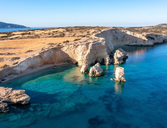 Greece, small Cyclades islands. Kato Koufonisi secluded beaches aerial drone view. Rocky cliffs over clear turquoise sea water. Sunny day, tranquil summer vacation destination for yacht charters.