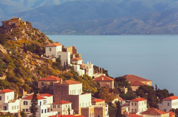 The historical white mansions with red roofs on hillside in Hydra, Greece