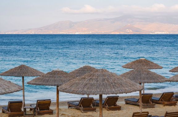 Sunbathing chairs and straw umbrellas on Plaka Beach, Naxos in Greece