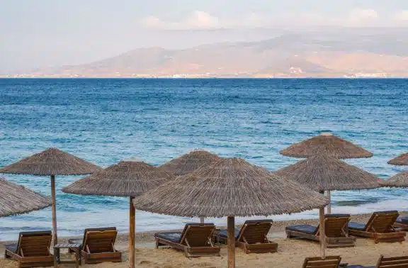 Sunbathing chairs and straw umbrellas on Plaka Beach, Naxos in Greece