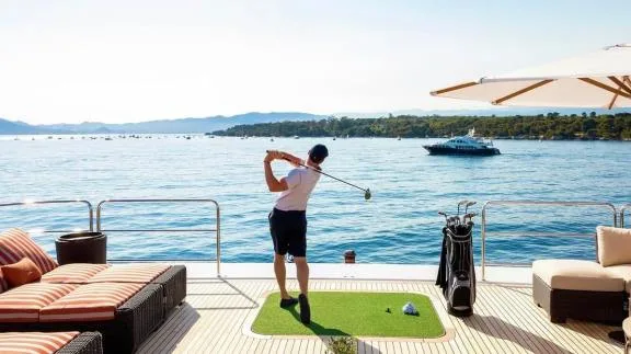 Guest practicing golf on a yacht aft deck in Greece.