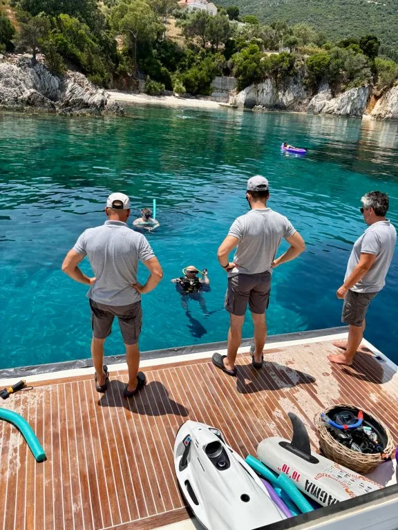 Yacht crew assisting guests with snorkeling and water sports from the swim platform.