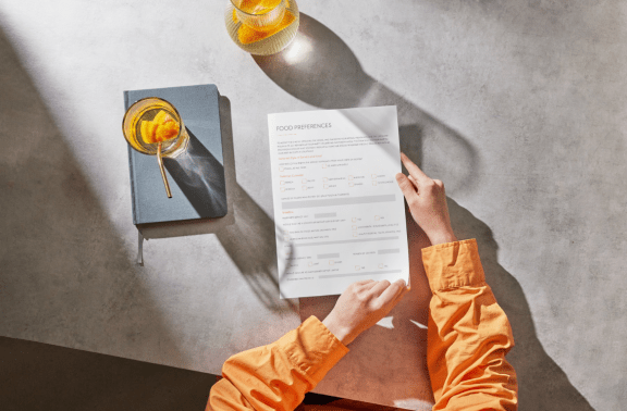 Yacht Charter Preference sheet held on a table beside two drinks and a notebook, photographed from above.