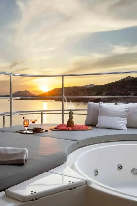 The spacious unobstructed sundeck has a jacuzzi pool with a large sunbathing area all around it, a bar, a dining table and sunbeds