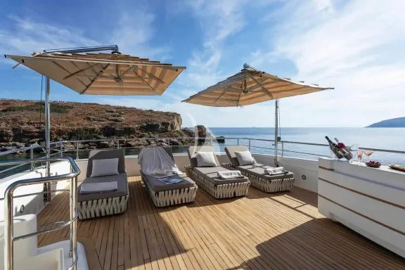 The spacious unobstructed sundeck has a jacuzzi pool with a large sunbathing area all around it, a bar, a dining table and sunbeds