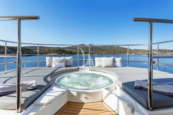 The spacious unobstructed sundeck has a jacuzzi pool with a large sunbathing area all around it, a bar, a dining table and sunbeds